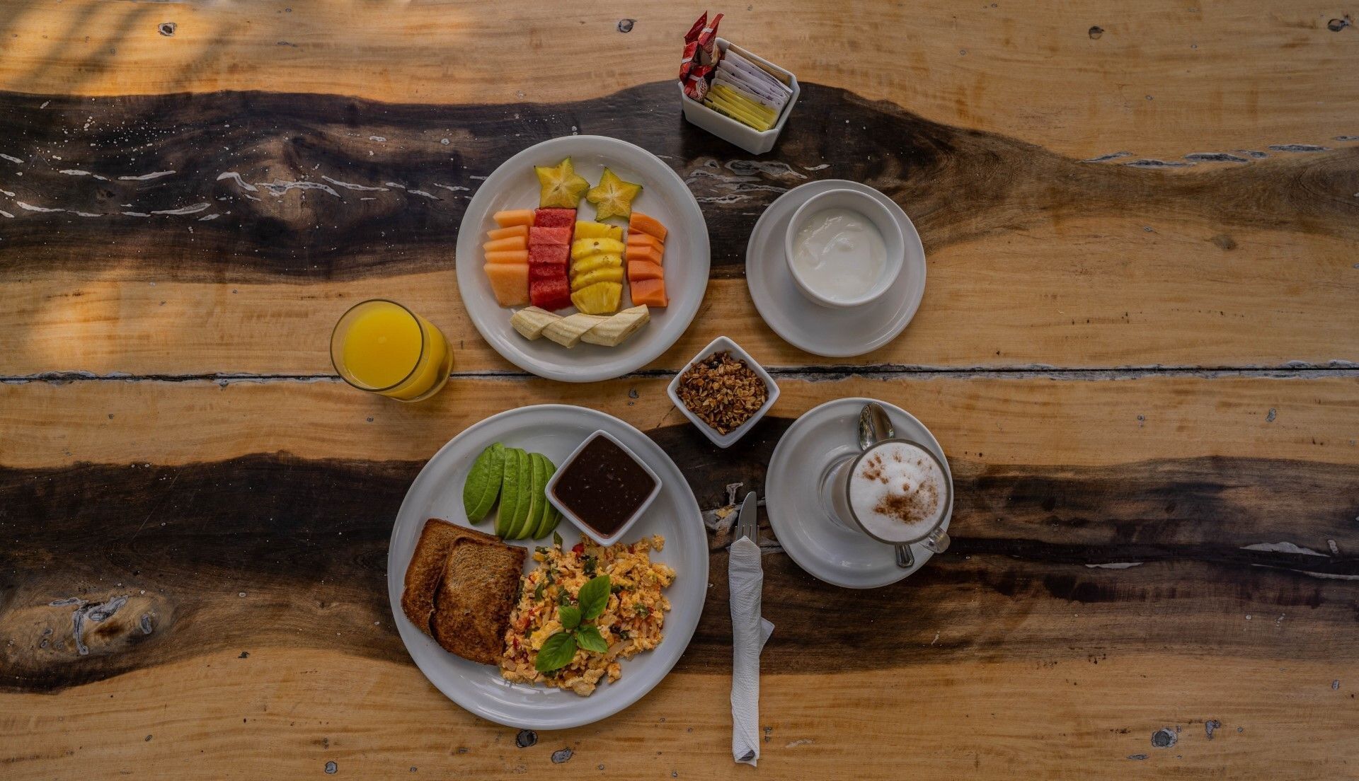 Desayuno con fruta, huevos y jugo en una mesa de madera